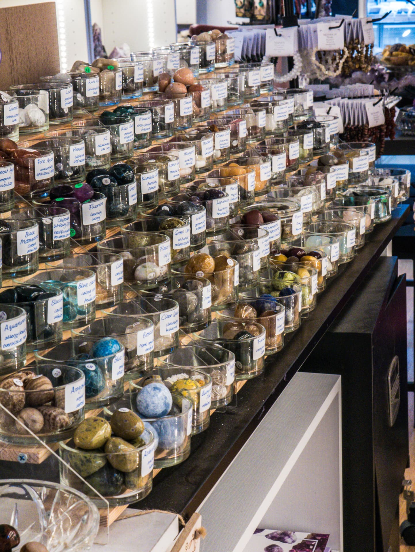 Rows of labelled tumbled crystals in glass bowls along the counter at Hidden Treasures York